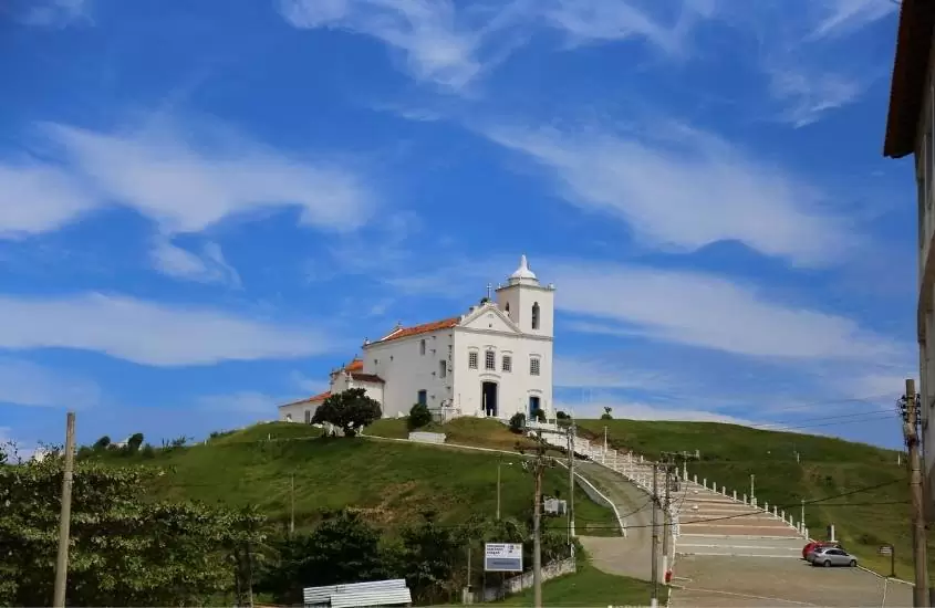 igreja branca sob céu azul, durante o dia, no topo de montanha em saquarema