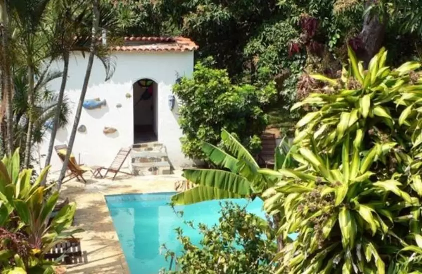 piscina cercada de árvores em dia ensolarado em hotel eco sítio nosso paraíso em saquarema