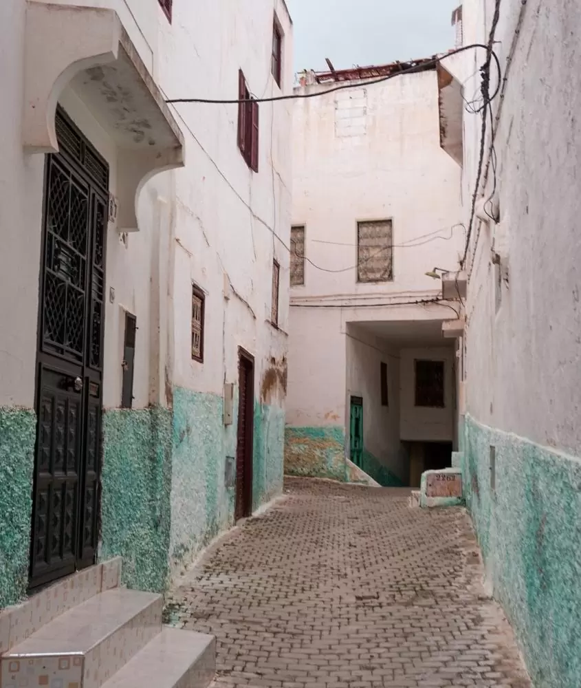 beco com casas brancas e verdes em moulay idriss, uma cidade considerada sagrada no marrocos