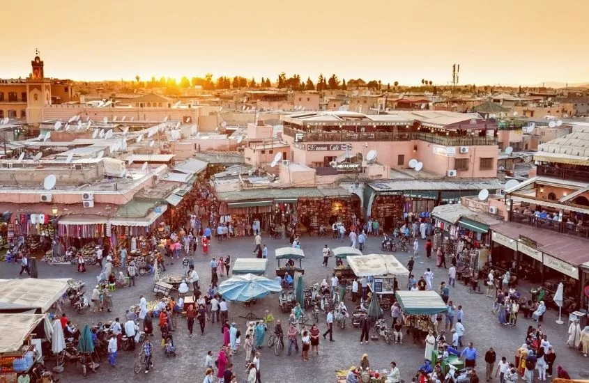 vista aérea de praça em marrakesh durante o entardecer, onde há barracas e pessoas caminhando