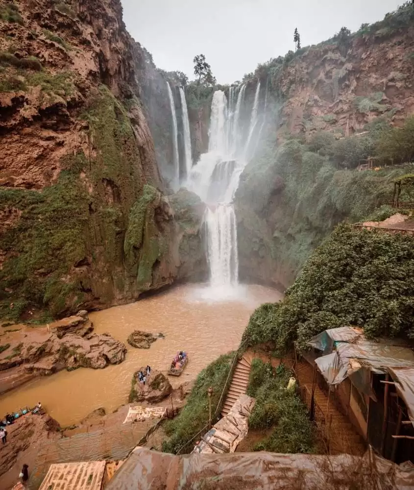 quedas d’agua rodeadas por montanhas e árvores em cachoeiras de ouzoud, um dos pontos turísticos do marrocos