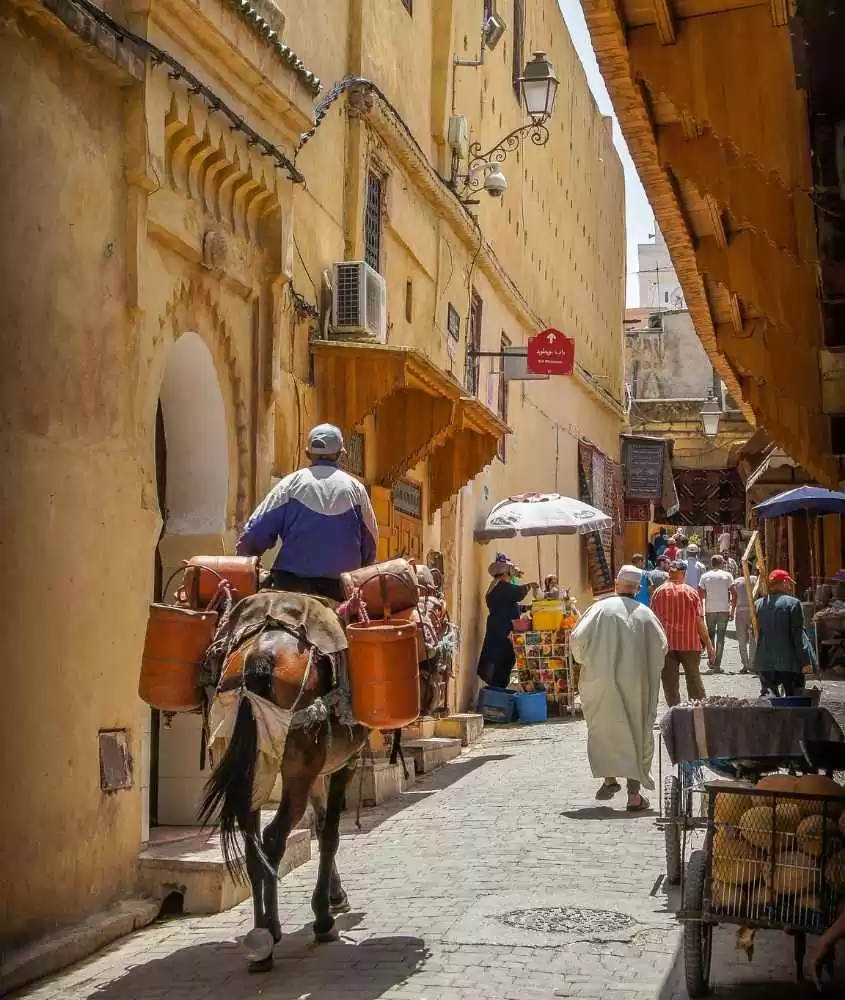 homem andando a cavalo e pessoas caminhando em beco no marrocos