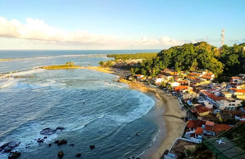 vista aérea de casas, montanhas e mar em Morro de São Paulo, destino para viagem pelo litoral brasileiro