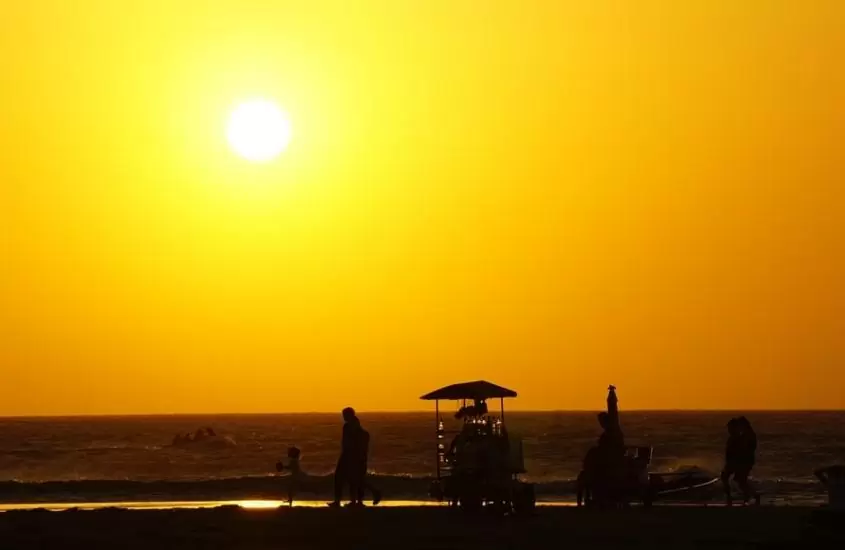 pessoas caminham em praia durante pôr do sol em jericoacoara