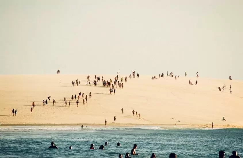 diversas pessoas em dunas e no mar, durante o dia, em jericoacoara
