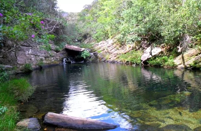 piscina natural de cachoeira véu da noiva, cercada de árvores, durante o dia em serra do cipó