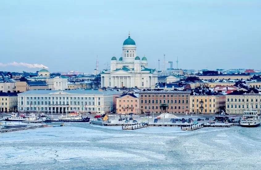 mesquita de concreto branco em frente a rio congelado, durante o dia, em helsinque, capital da finlândia que é uma das cidades mais frias do mundo