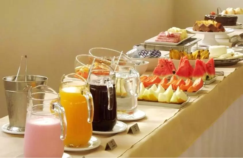 mesa com garrafas de suco, frutas e bolos em hotel metrópole, um dos hotéis em belo horizonte