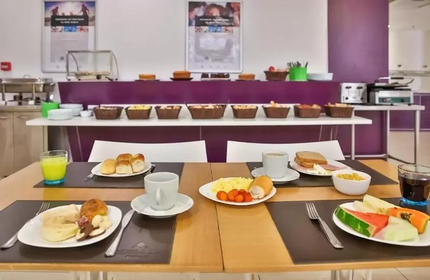 pratos com pães, bolos e frutas em cima de mesa de restaurante de nobile inn pampulha, um dos hotéis em belo horizonte