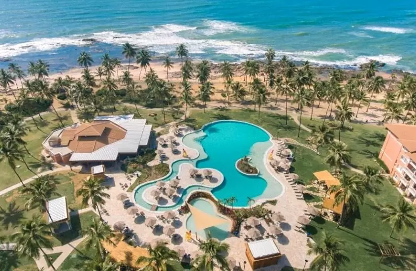 vista aérea de piscinas rodeadas de coqueiros em sauípe premium brisa, um dos melhores resorts all inclusive no brasil para lua de mel em frente à praia, em costa do sauipe