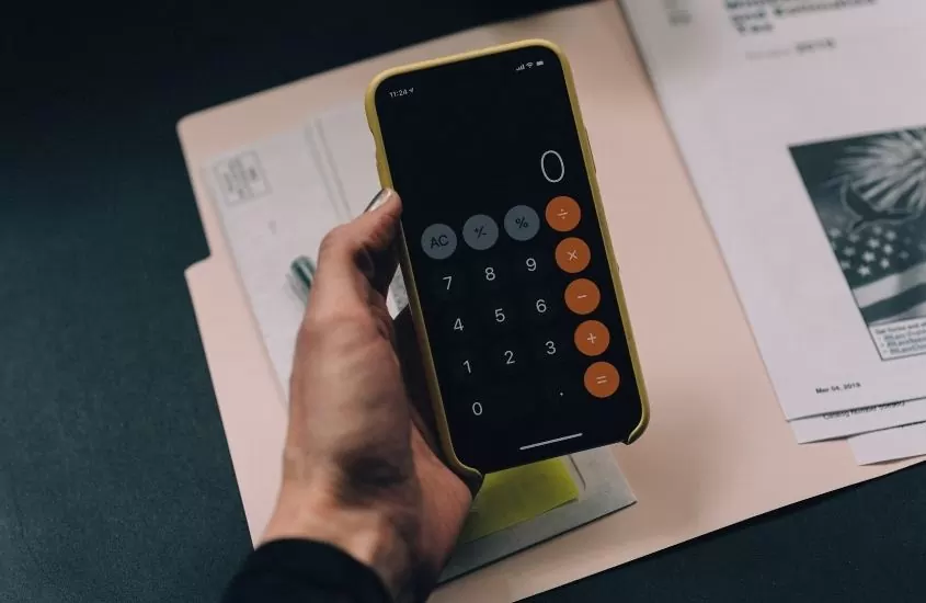 pessoa segura celular, onde aplicativo de calculadora está aberto mostrando o número zero