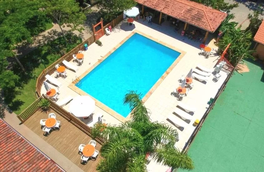 vista aérea de espreguiçadeiras, mesas e guarda-sóis em frente a piscina de Hotel São Sebastião da Praia, durante dia ensolarado em Florianópolis