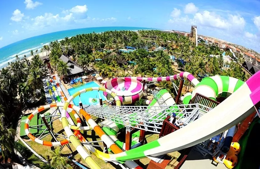vista aérea de toboáguas, piscinas, árvores e praia ao fundo, durante dia ensolarado em beach park, um dos melhores parques de diversões do brasil