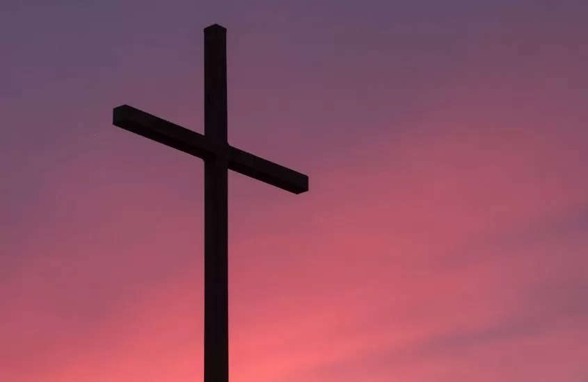 cruz marrom com céu rosa e azul, durante entardecer