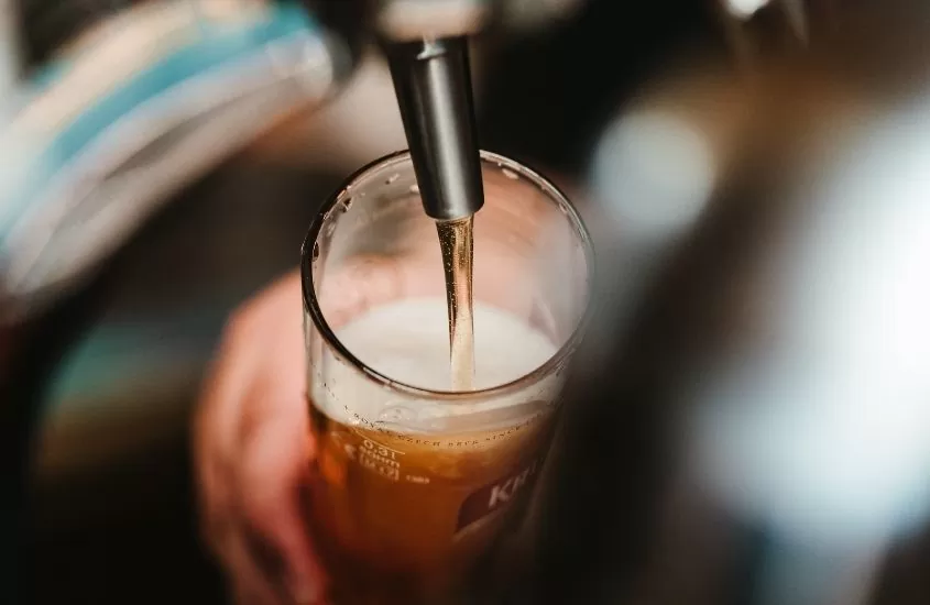 pessoa enche copo de vidro com cerveja em Pub & Bar Quiosque do Vargas, uma ótima programação para quem busca o que fazer em penha sc a noite