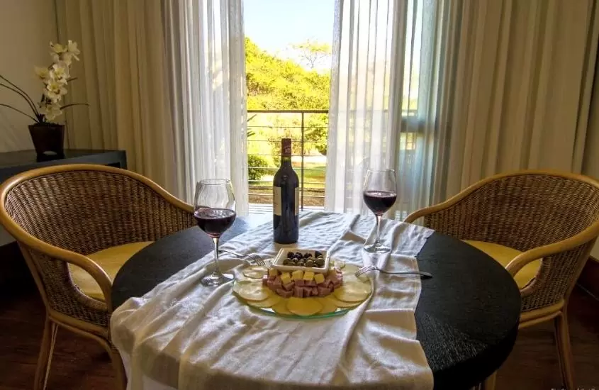 mesa posta para dois com tabua de frios e vinho em quarto do garden hill hotel e golfe, uma ótima opção entre as pousadas românticas mg