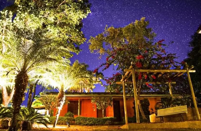 fachada cercada de árvores do espaço vilarejo pousada em noite estrelada em serra do cipó