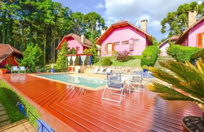 chalés rosas em frente a piscina, durante dia ensolarado, em pousada ana terra, uma das melhores pousadas românticas em minas gerais, localizada em monte verde