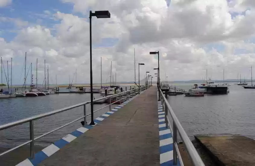 Em um dia de sol com nuvens, ponte do porto com barcos ao redor e praia na frente