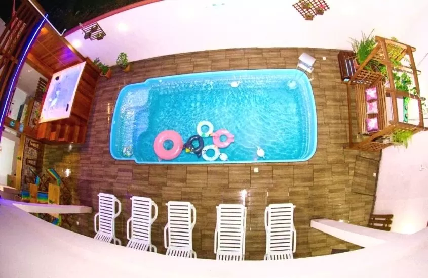 vista de cima de espreguiçadeiras, piscinas e banheira de hidromassagem em área de lazer interna de Pousada Joana Guest House
