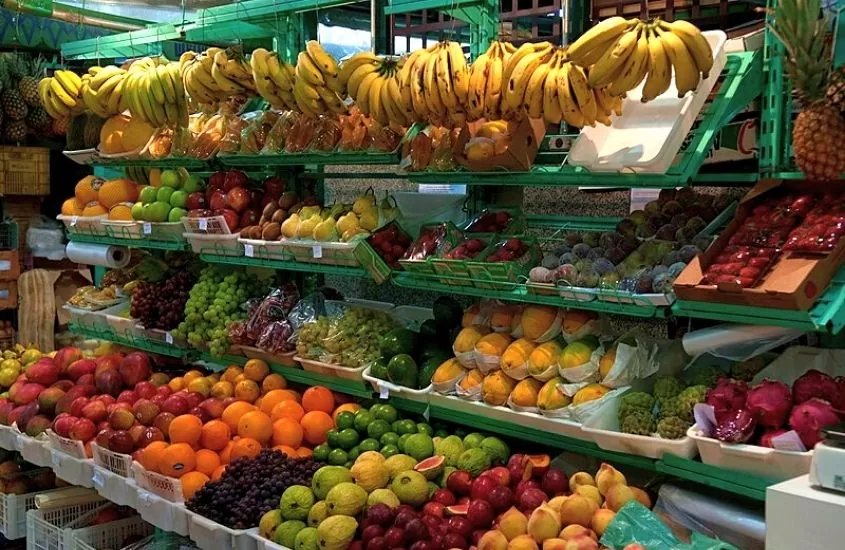 bananas, morangos, abacaxi e uvas dispostos para venda em mercado municipal, um dos melhores passeios em Curitiba
