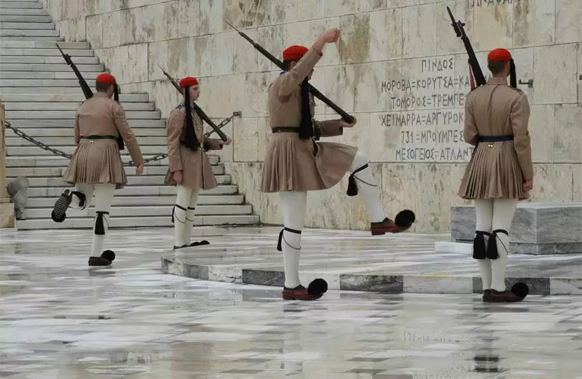 Em um dia nublado, praça com soldados gregos e escadaria ao lado
