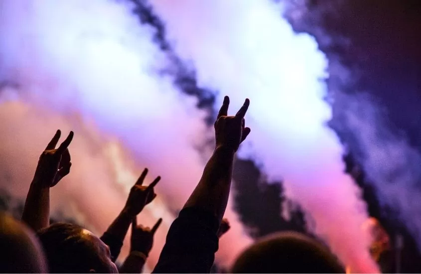pessoas fazendo símbolo de rock com as mãos, durante show