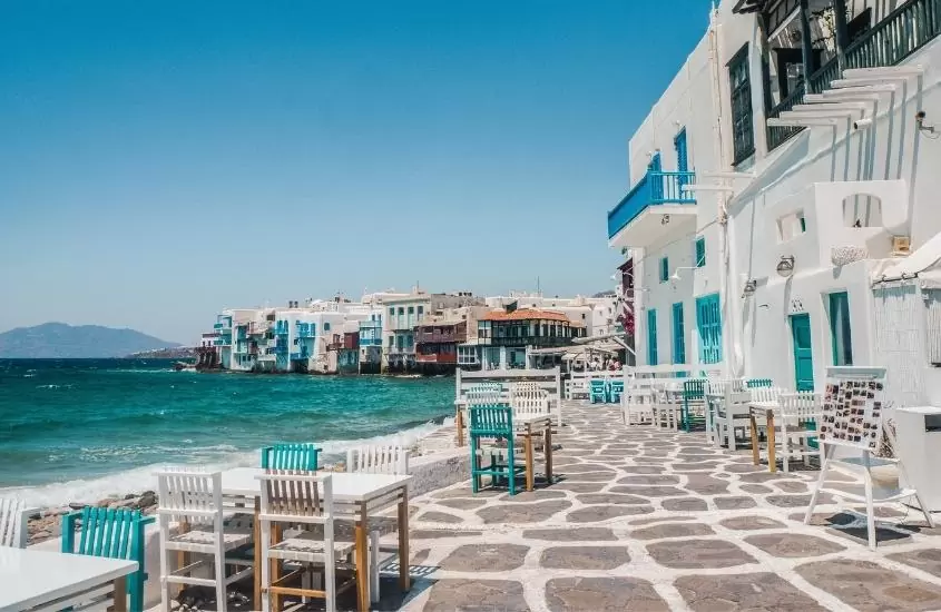mesas e cadeiras em rua à beira-mar, durante o dia em little venice, região romântica de mykonos