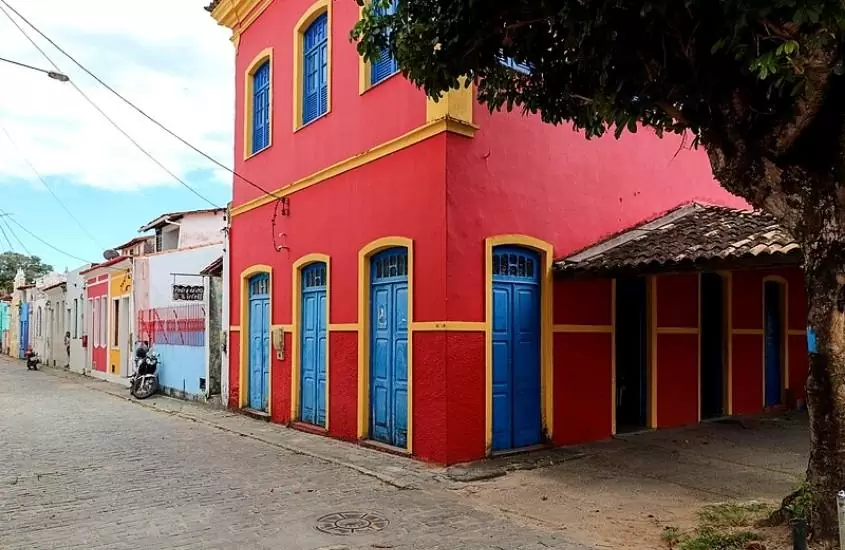 casa vermelha com detalhes amarelos e portas e janelas azuis em rua de centro histórico da ilha de itaparica ba, durante o dia