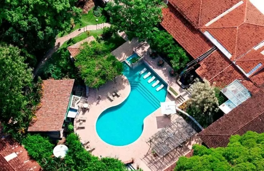 durante dia ensolarado, vista aérea de piscina cercada de árvores em área de lazer do Hotel de Lençóis