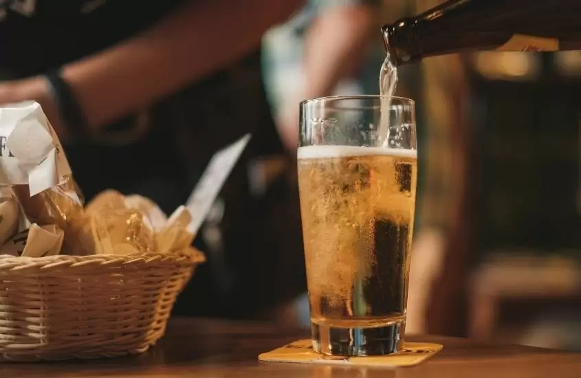 copo de vidro com cerveja em cima de mesa de bar