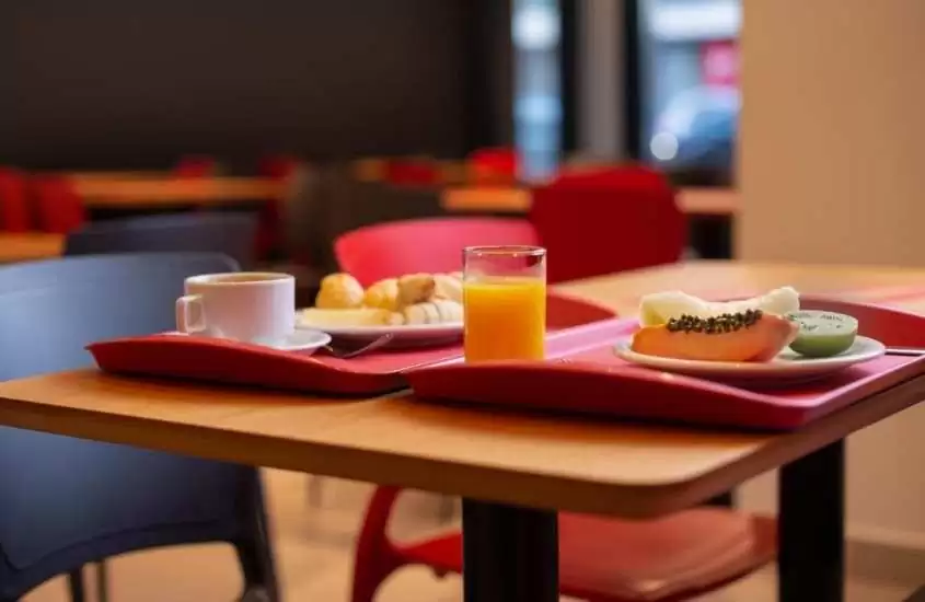 café, pães, suco e frutas em cima de bandeja em mesa de hotel moov porto alegre