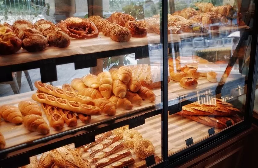 balcão de vidro onde há exposto diversos tipos de pães, como amanteigado, australiano e grego, vendidos nos melhores lugares para comer em curitiba