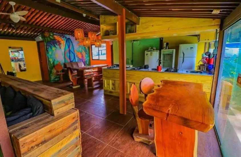 mesas de madeira, geladeiras e balcão com fogão e pia em cozinha de Boldró Surf House