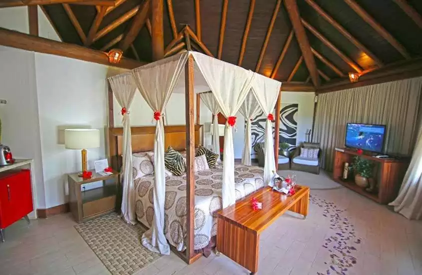frigobar vermelho, cama de casal e poltronas em bangalô em uma das melhores pousadas em fernando de noronha