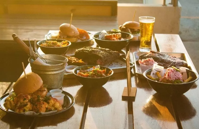 hamburguer, carne e cerveja em cima de mesa de madeira em bar