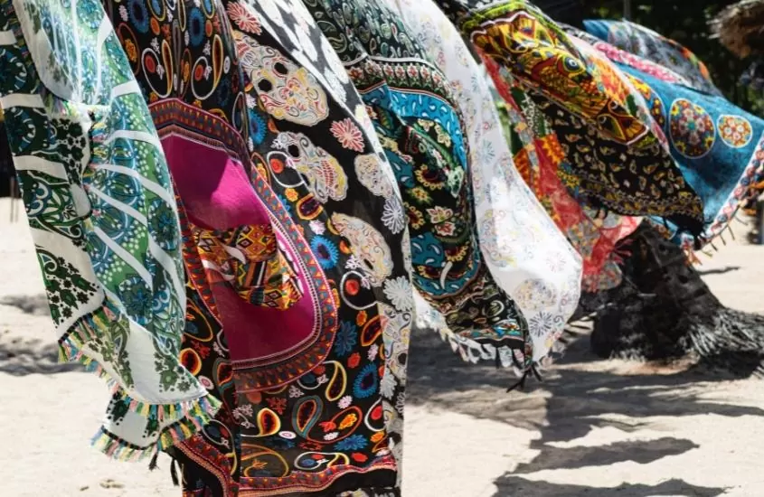 diversas cangas coloridas expostas para venda em praia, durante o dia