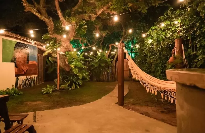 rede de descanso em jardim, durante a noite, em Pousada Luzes de Caraíva