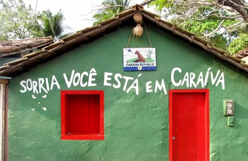 Casa verde onde há escrito em branco a frase: Sorria, você está em Caraíva