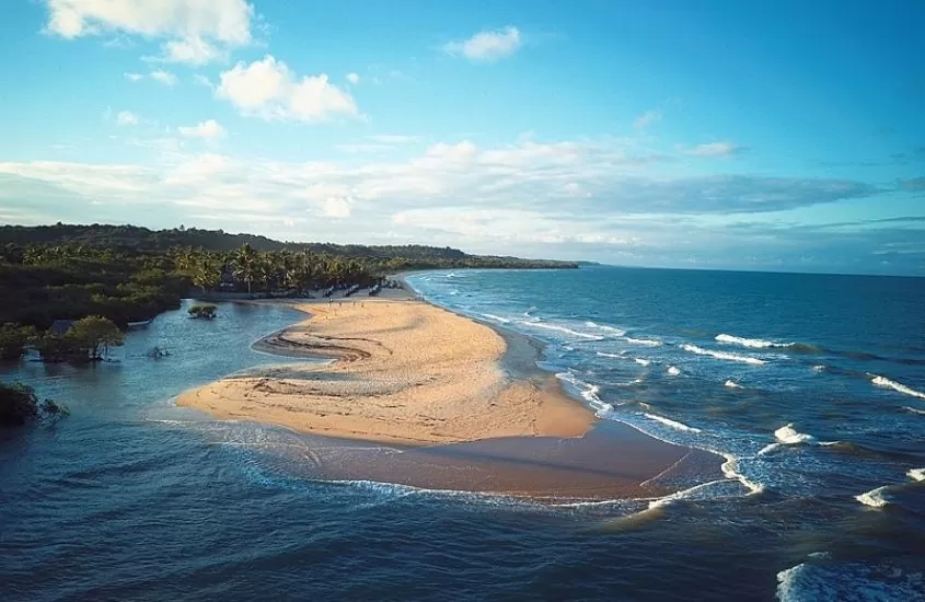 vista aérea de areia dividindo mar e rio, durante o dia em praia da barra, um dos melhores passeios em caraíva