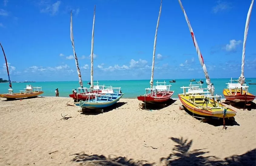 barcos coloridos atracados em areia, durante o dia, em pajuçara um dos melhores passeios em maceio