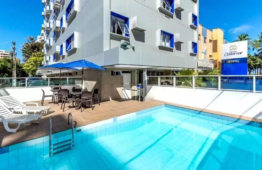 espreguiçadeiras em frente a piscina, durante dia ensolarado em área de lazer de Hotel Costamar, um dos melhores hoteis em maceio