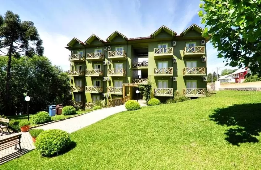 durante o dia, jardim em frente a construção verde de 4 andares com varandas, onde funciona Villa Flor Ecoresort