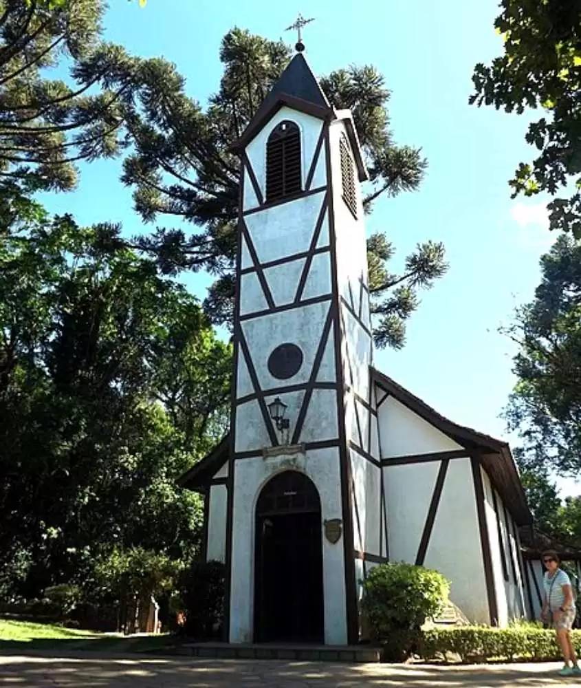 torre de igreja branca com detalhes marrons, rodeada de árvores, durante o dia em Nova Petrópolis RS