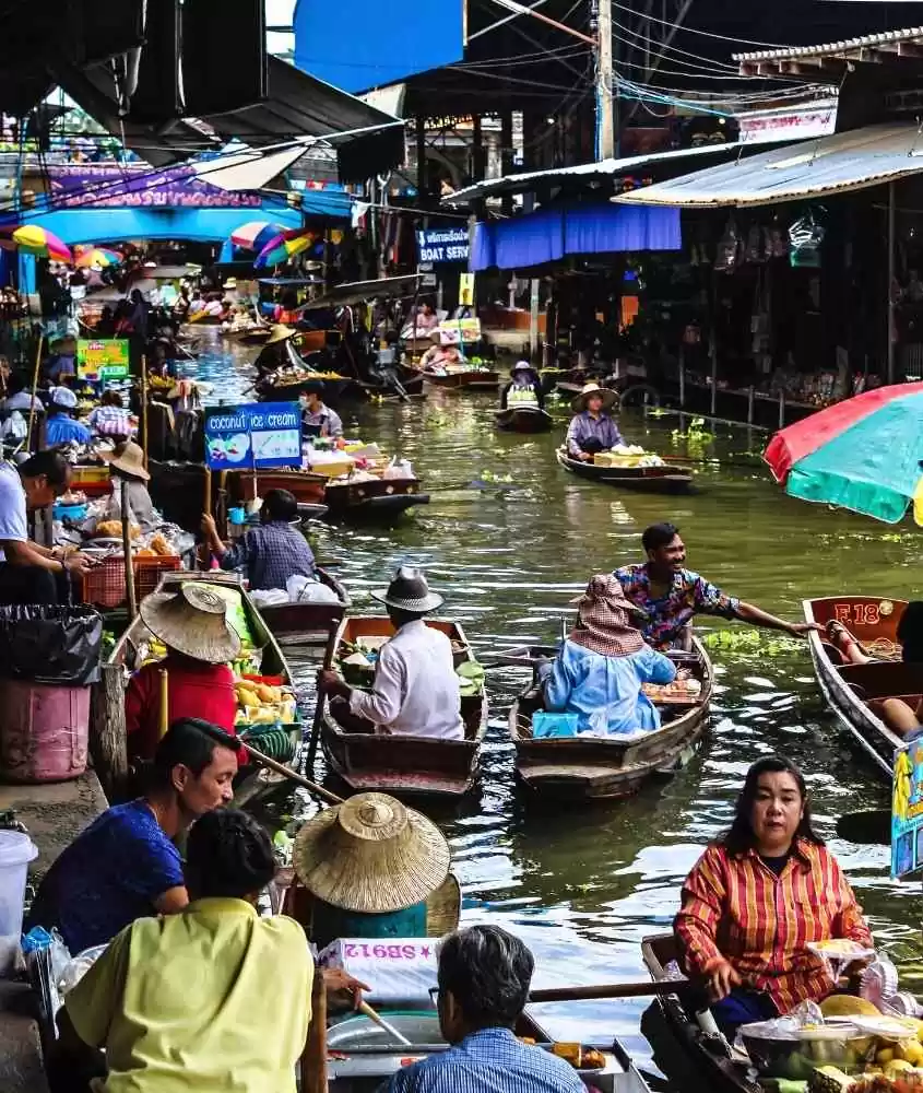 pessoas em canoas com mercadorias atravessando canal na Tailândia, durante o dia