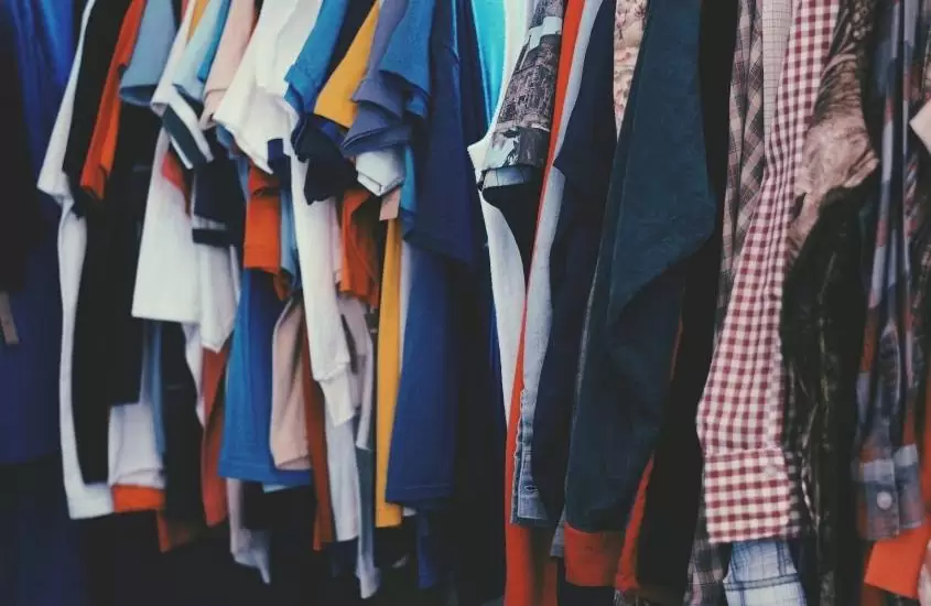diversas blusas coloridas em cabideiro de loja