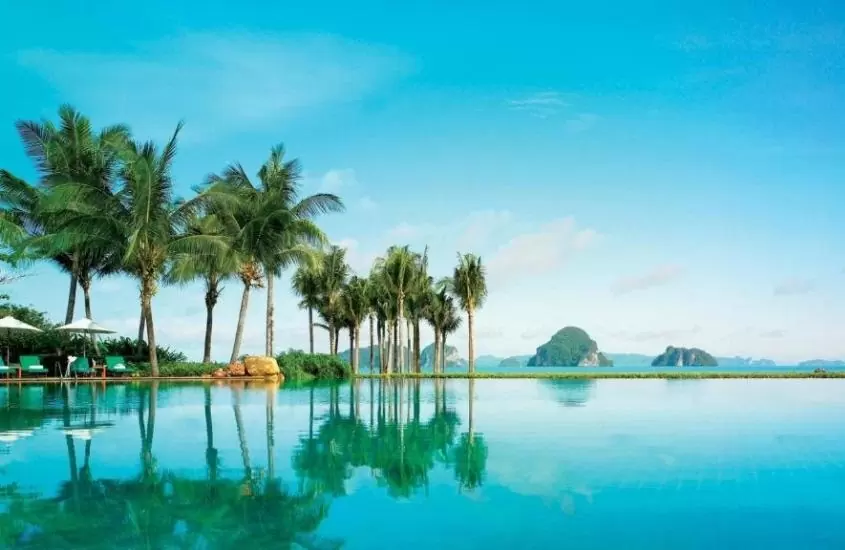 durante o dia, coqueiros em frente a grande piscina com vista para o mar em área de lazer de Phulay Bay, A Ritz-Carlton Reserve