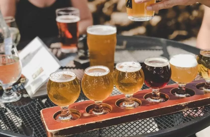 taças de vidro lado a lado, cheias de cerveja em cima de mesa de bar