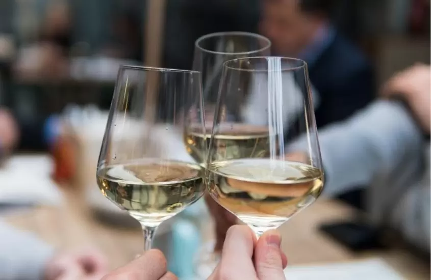 pessoas brindam com taças de vidro com vinho branco
