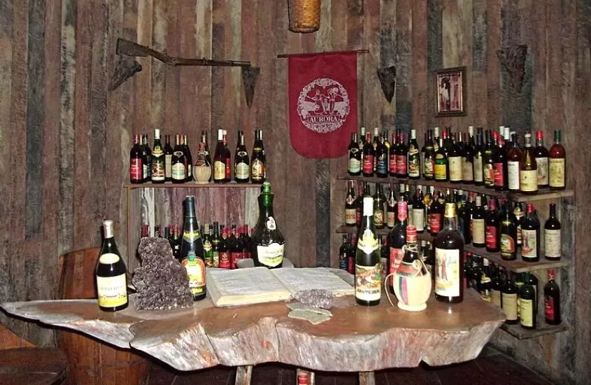 diversas garrafas de vinho lado a lado em prateleiras e mesa em interior de Vinícola Aurora, uma das vinícolas no vale dos vinhedos